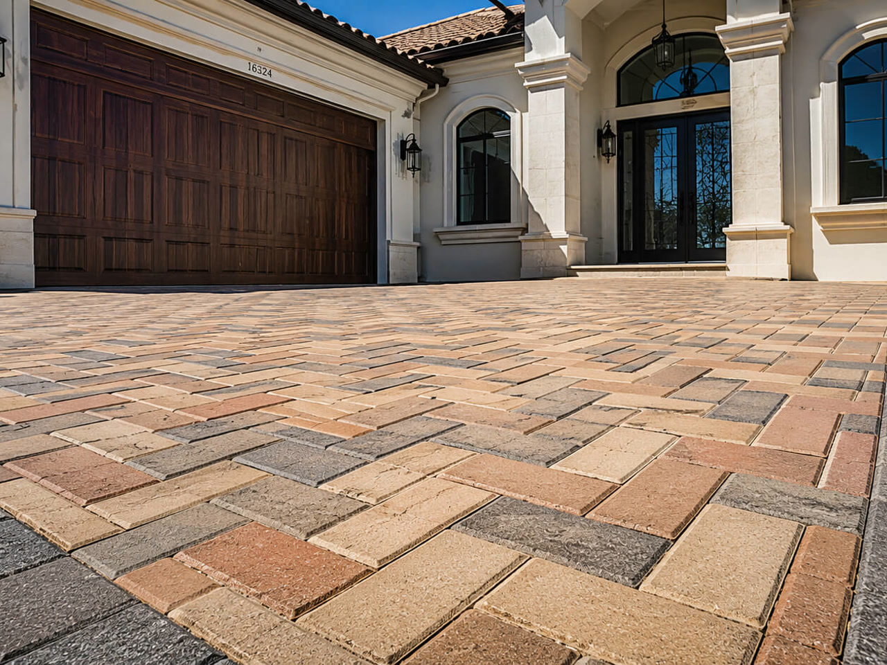 Paver driveway in a blended tan and terracotta herringbone pattern with a charcoal border, leading to a Mediterranean style home on a Boynton Beach property