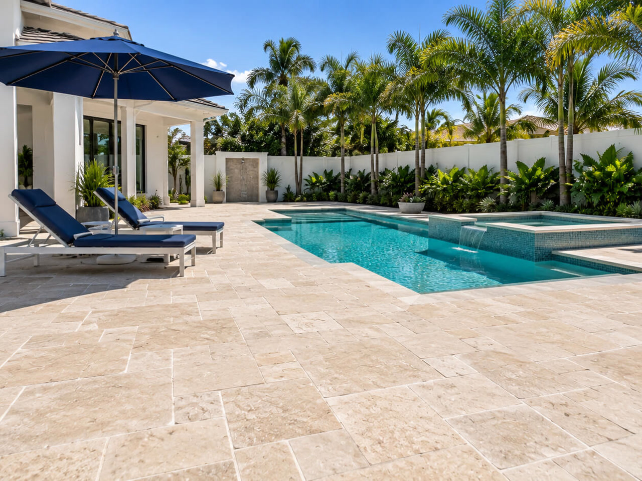 Ivory travertine paver pool deck in a French pattern beside a pool with a raised spa and sheer descent, installed in Juno Beach