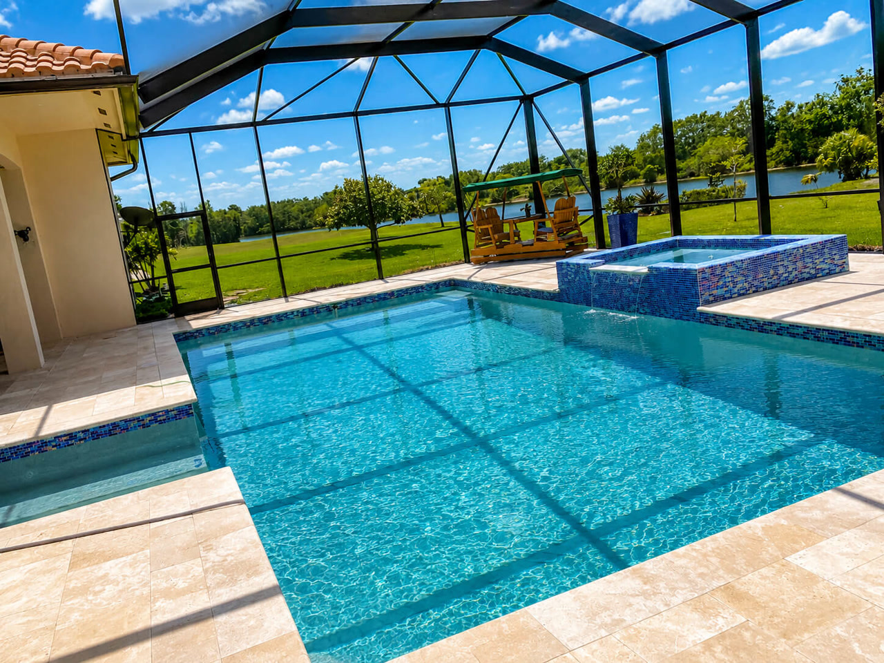 Renovated pool and raised spa with mosaic tile under a screen enclosure in a Juno Beach backyard