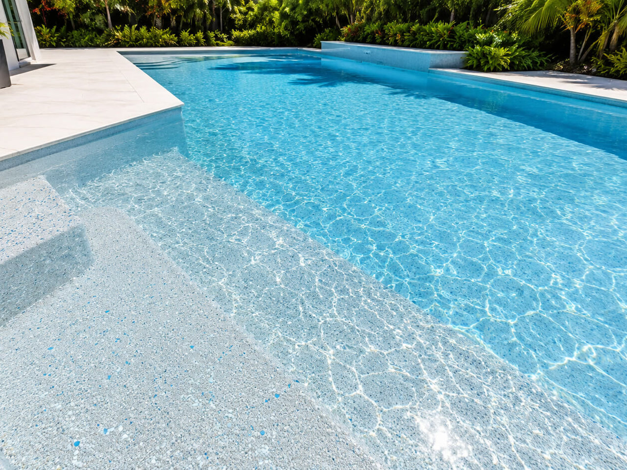Light pebble pool finish under clear water across wide entry steps and a sun shelf in a Boynton Beach backyard