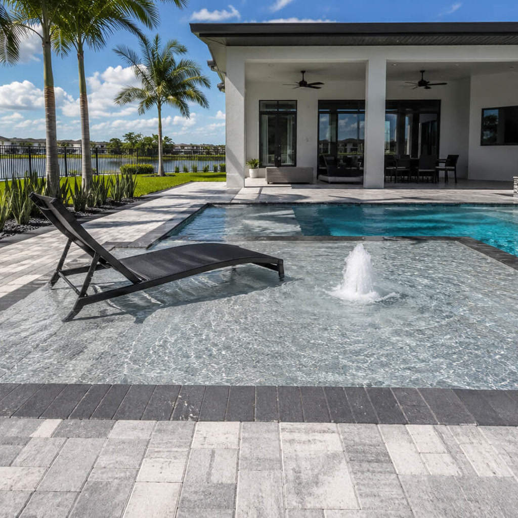 Sun shelf with a bubbler and in water lounger connecting the pool to a covered lanai in a Gulfstream backyard