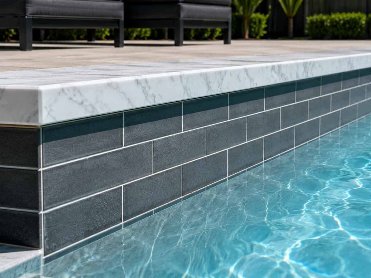 White marble coping cap over charcoal subway tile along a Coconut Creek pool wall